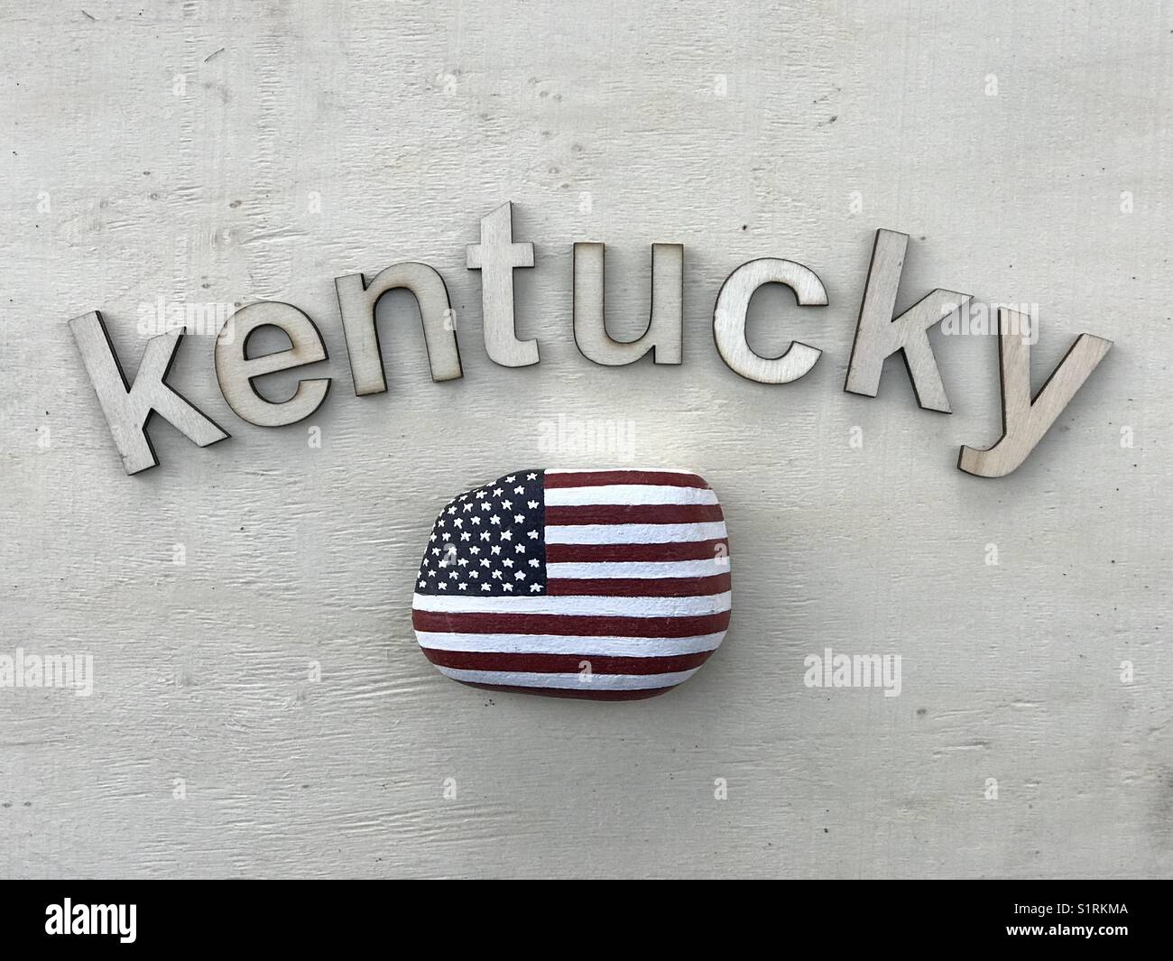 Kentucky, USA, souvenir con lettere in legno e bandiera nazionale degli Stati Uniti dipinta su una pietra - Immagine stock catturata con smartphone