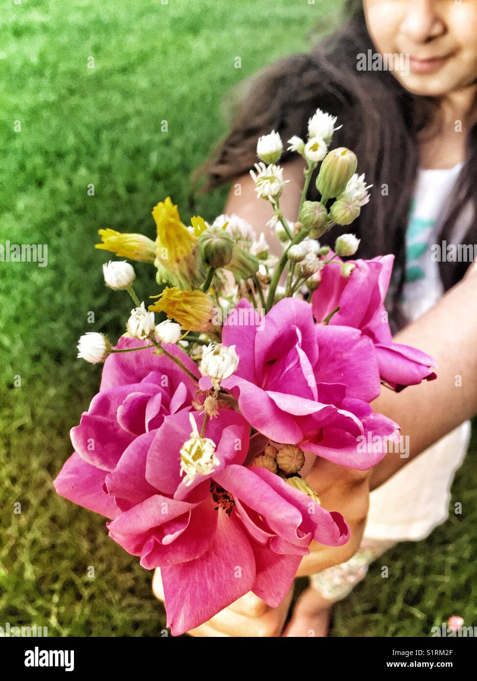 Bambina tenendo un selvaggio bouquet di fiori Foto Stock