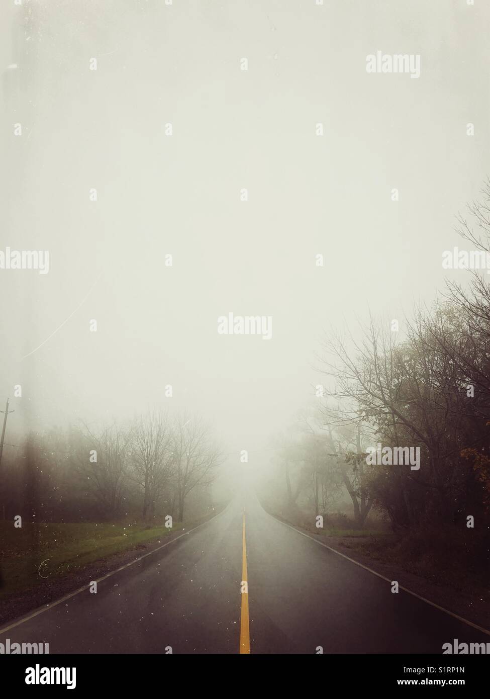 Vista delle piogge di guardare verso il basso vuoto road che scompare nella nebbia in rural ontario, Canada Foto Stock