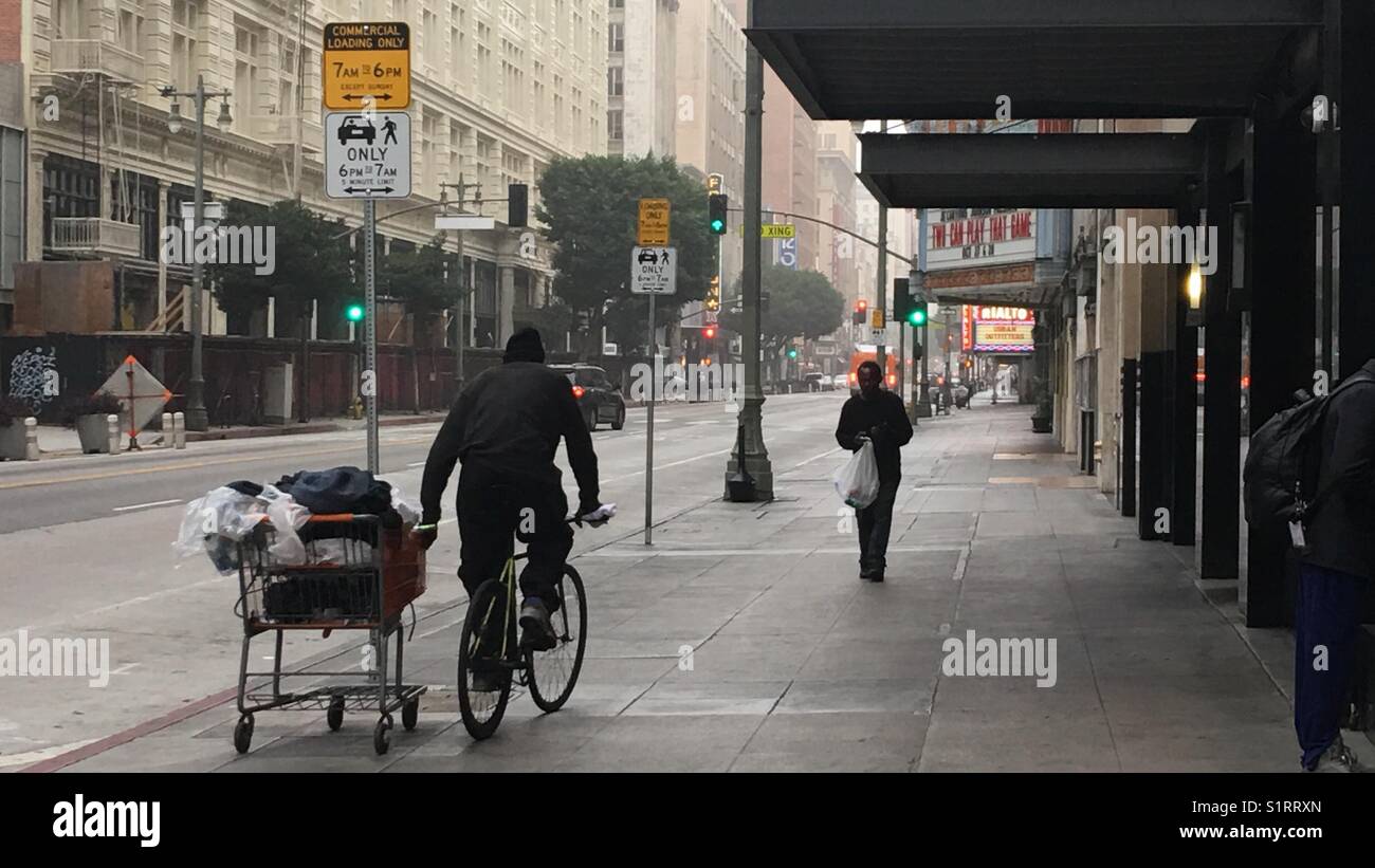 Uomo in bicicletta con effetti personali in un carrello a Broadway nel centro cittadino di Los Angeles - Immagine stock catturata con smartphone