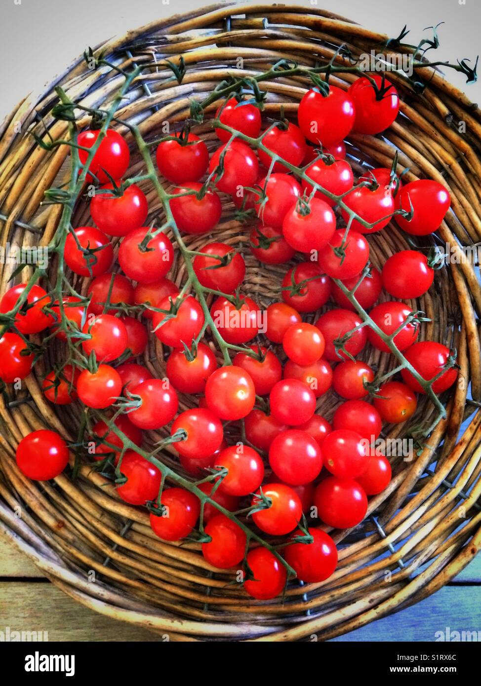 Pomodori ciliegini su un vassoio di vimini - Immagine stock catturata con smartphone