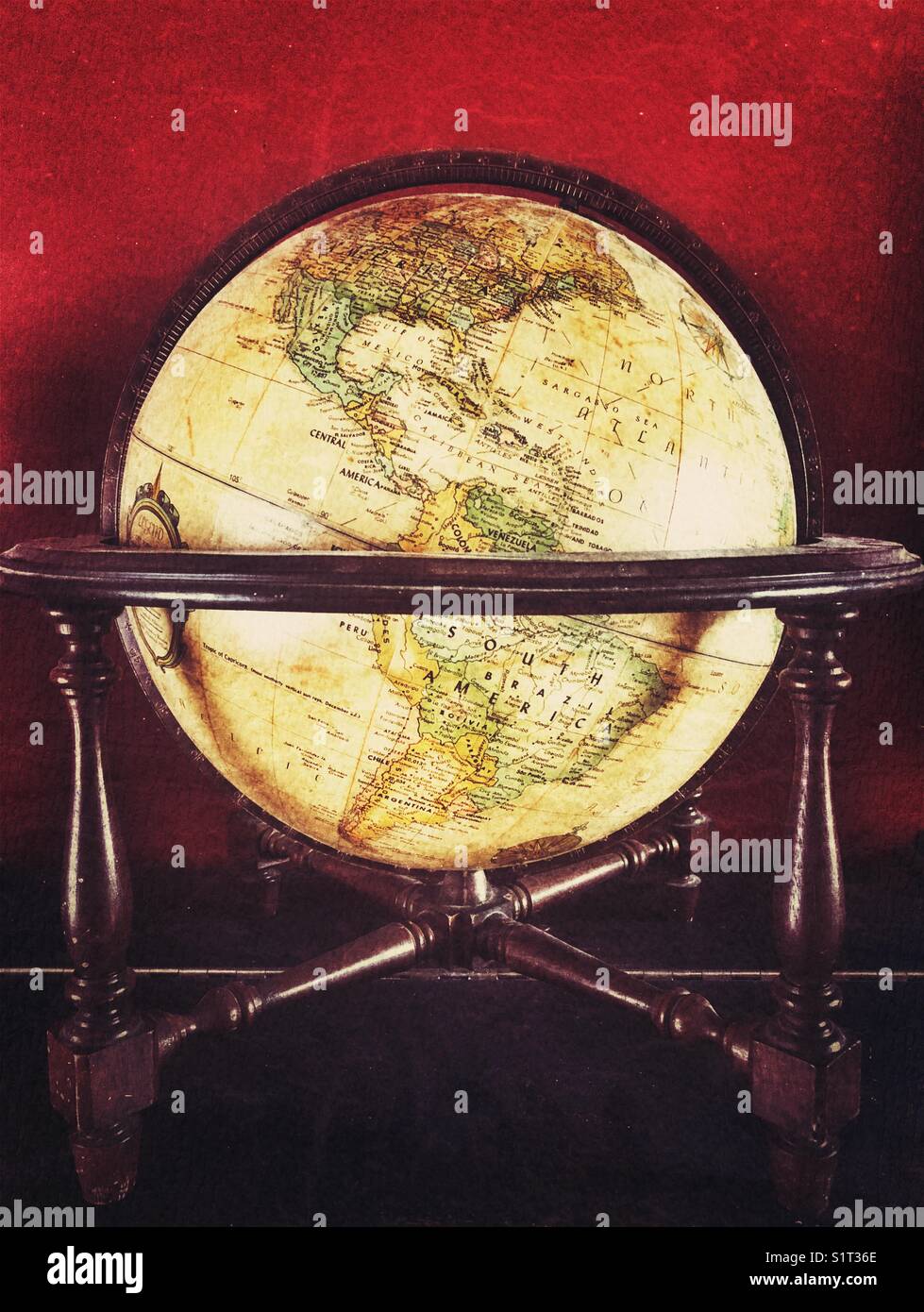 Globo del mondo antico in stand di legno con sfondo rosso scuro che mostra il Nord e il Sud America - Immagine stock catturata con smartphone