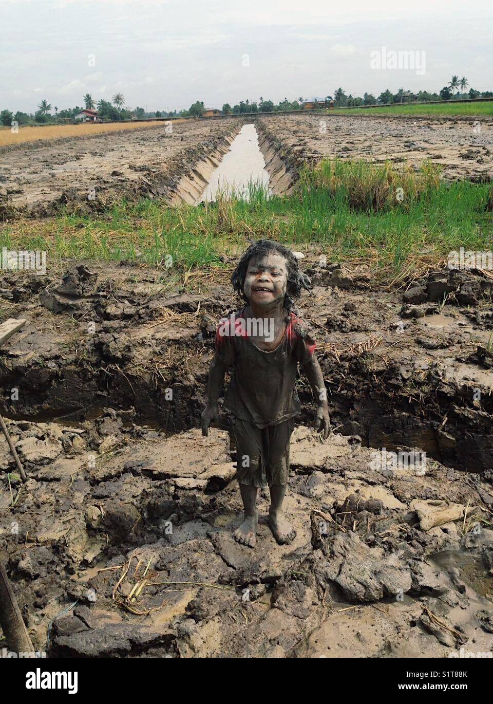 Ragazza nel fango da campo di riso Foto Stock