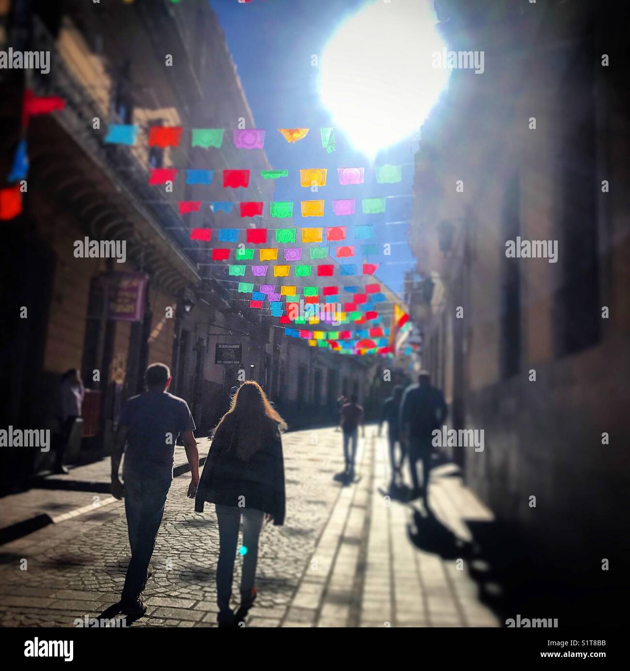 Un paio di turisti a piedi in una strada decorata con carta decorativa bandiere in Guanajuato, Messico Foto Stock