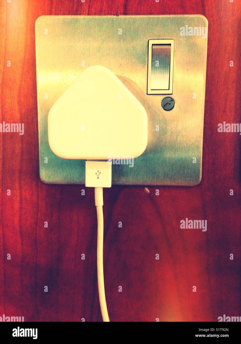 Un cavo USB collegato a un caricabatterie collegato a una presa elettrica. - Immagine stock catturata con smartphone