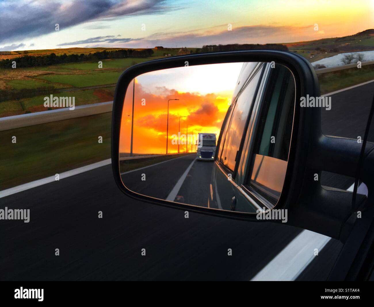 Un camion nel retrovisore sull'autostrada al tramonto. Foto Stock