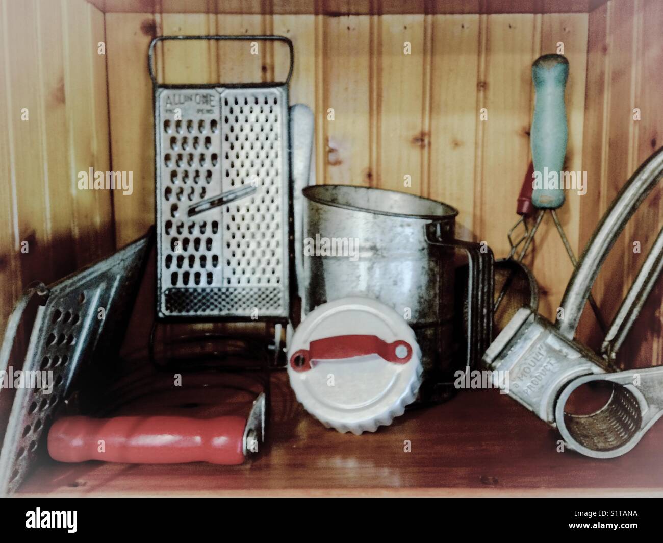 Collezione vintage di utensili da cucina di metallo contro il legno sullo sfondo del pannello Foto Stock