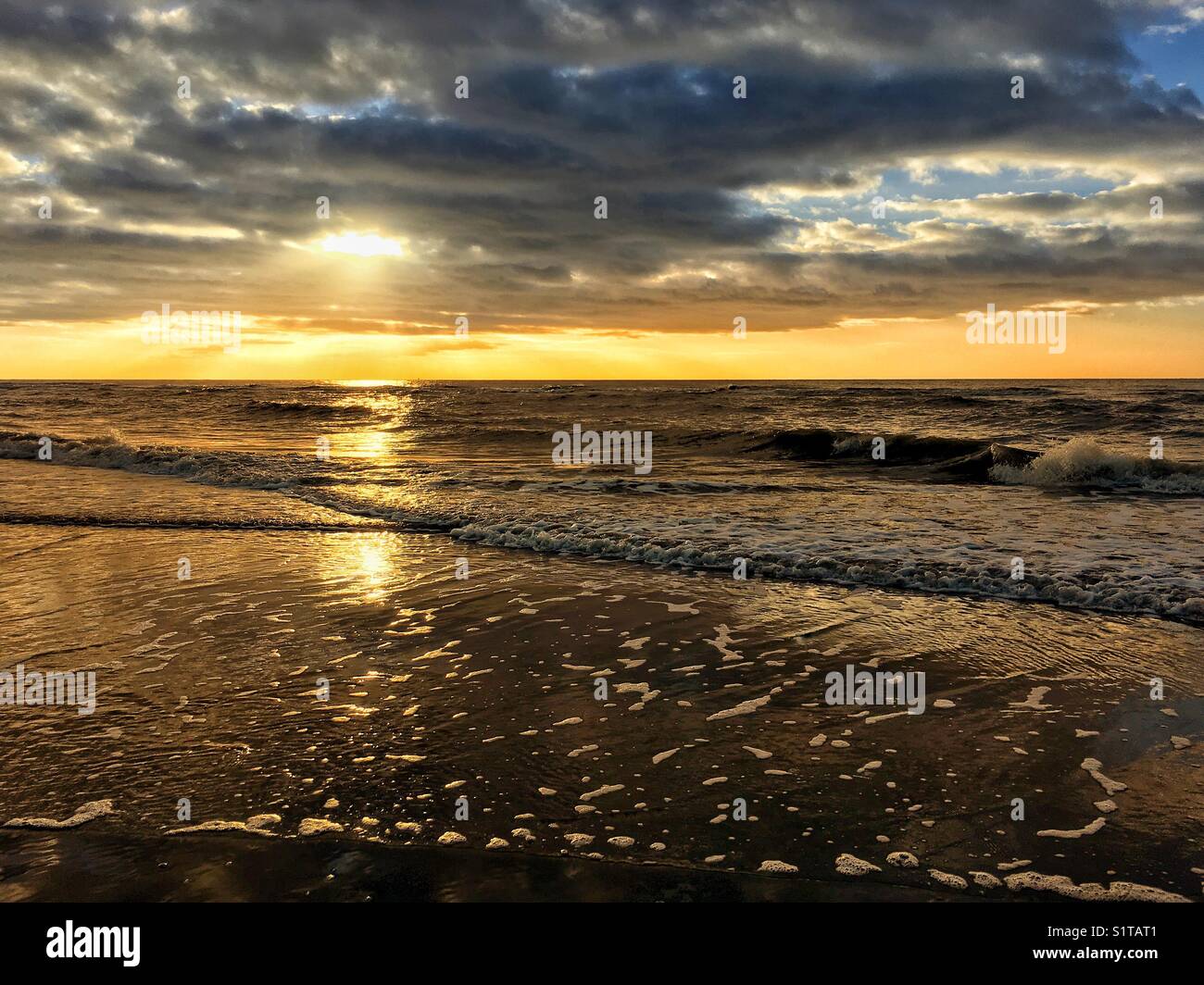 Il sole tramonta sulle onde infranti a Blackpool Foto Stock
