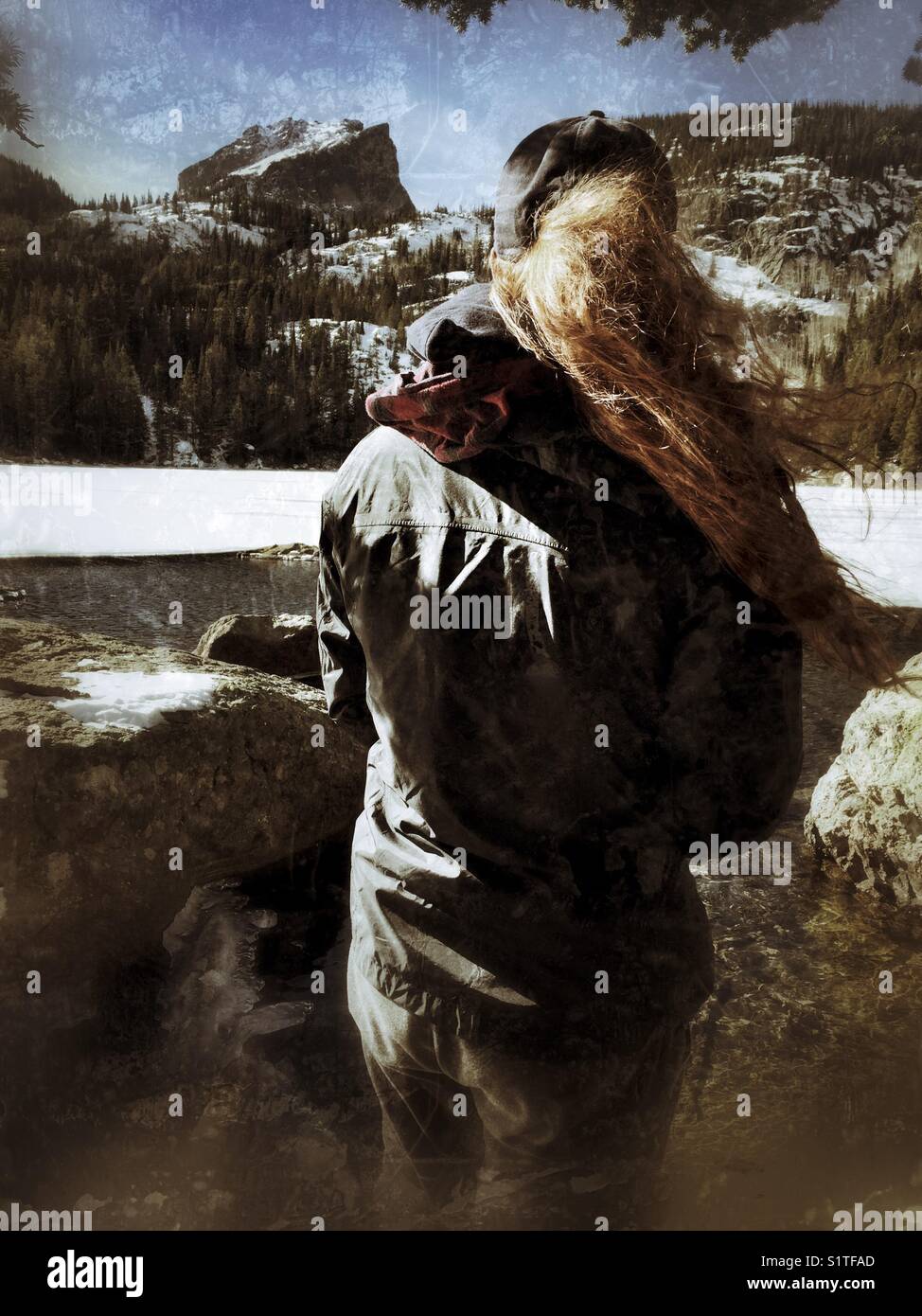 Una giovane donna guarda un bel lago e una catena montuosa - Immagine stock catturata con smartphone