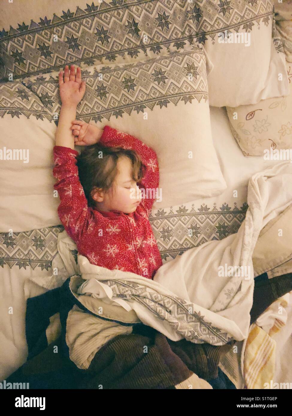 5 anno di età bambino che dorme con le braccia in alto sopra la testa nel letto con i genitori Foto Stock