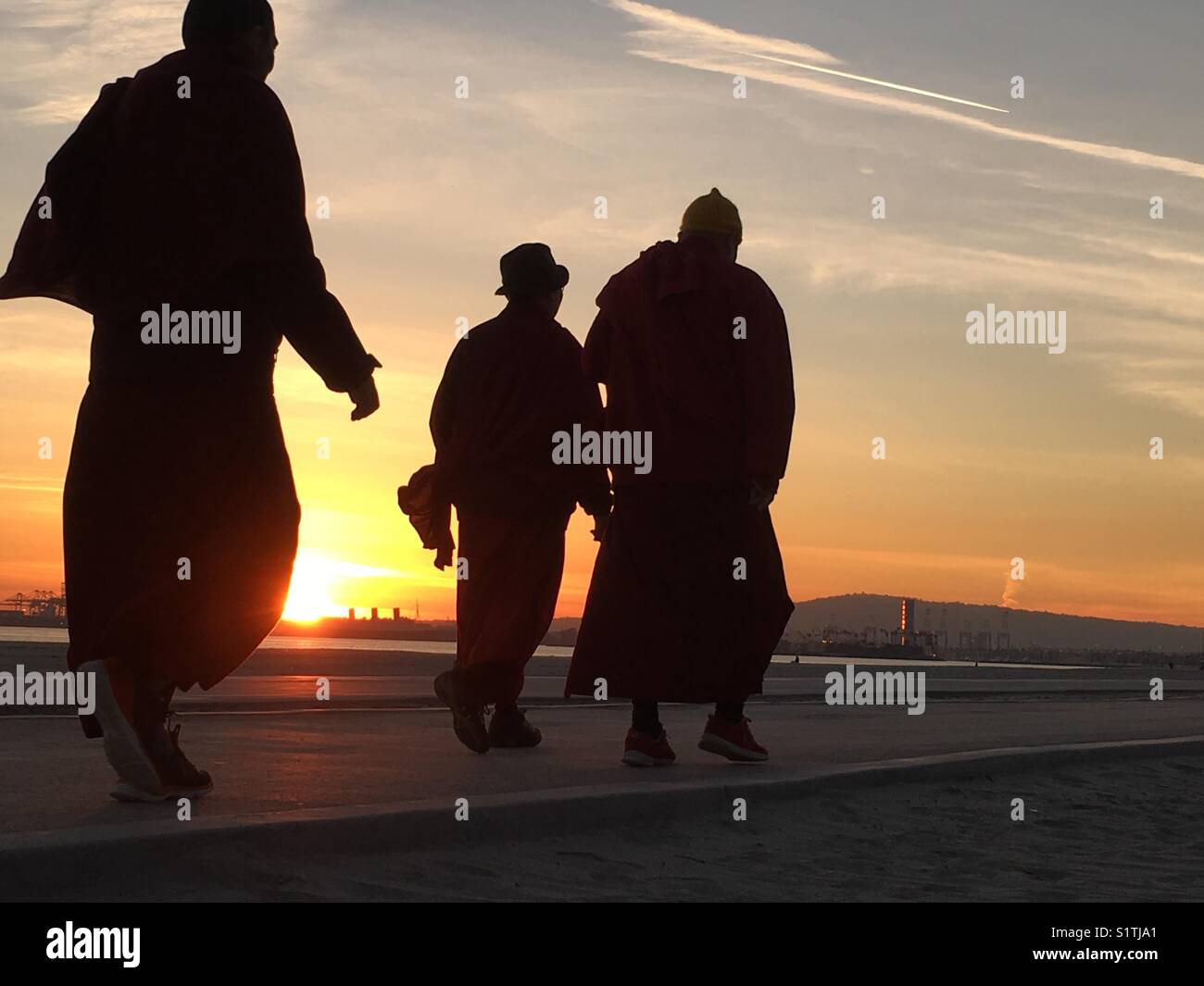 I monaci buddisti di camminare sulla spiaggia al tramonto a Long Beach, California, Stati Uniti d'America - Immagine stock catturata con smartphone