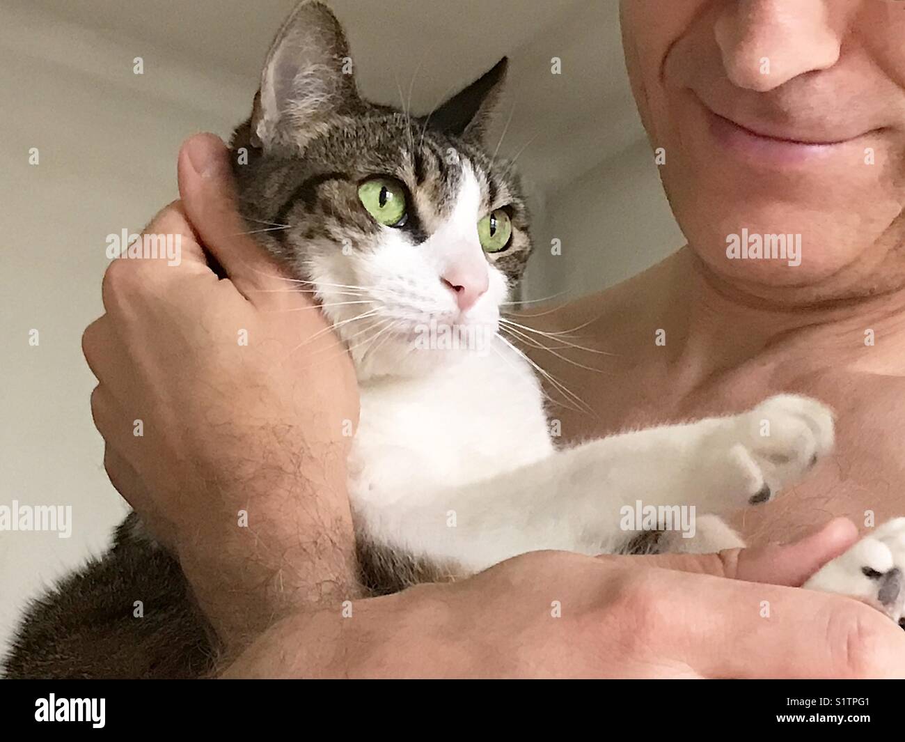 L'uomo tenendo un tabby e white cat nelle sue braccia. Foto Stock