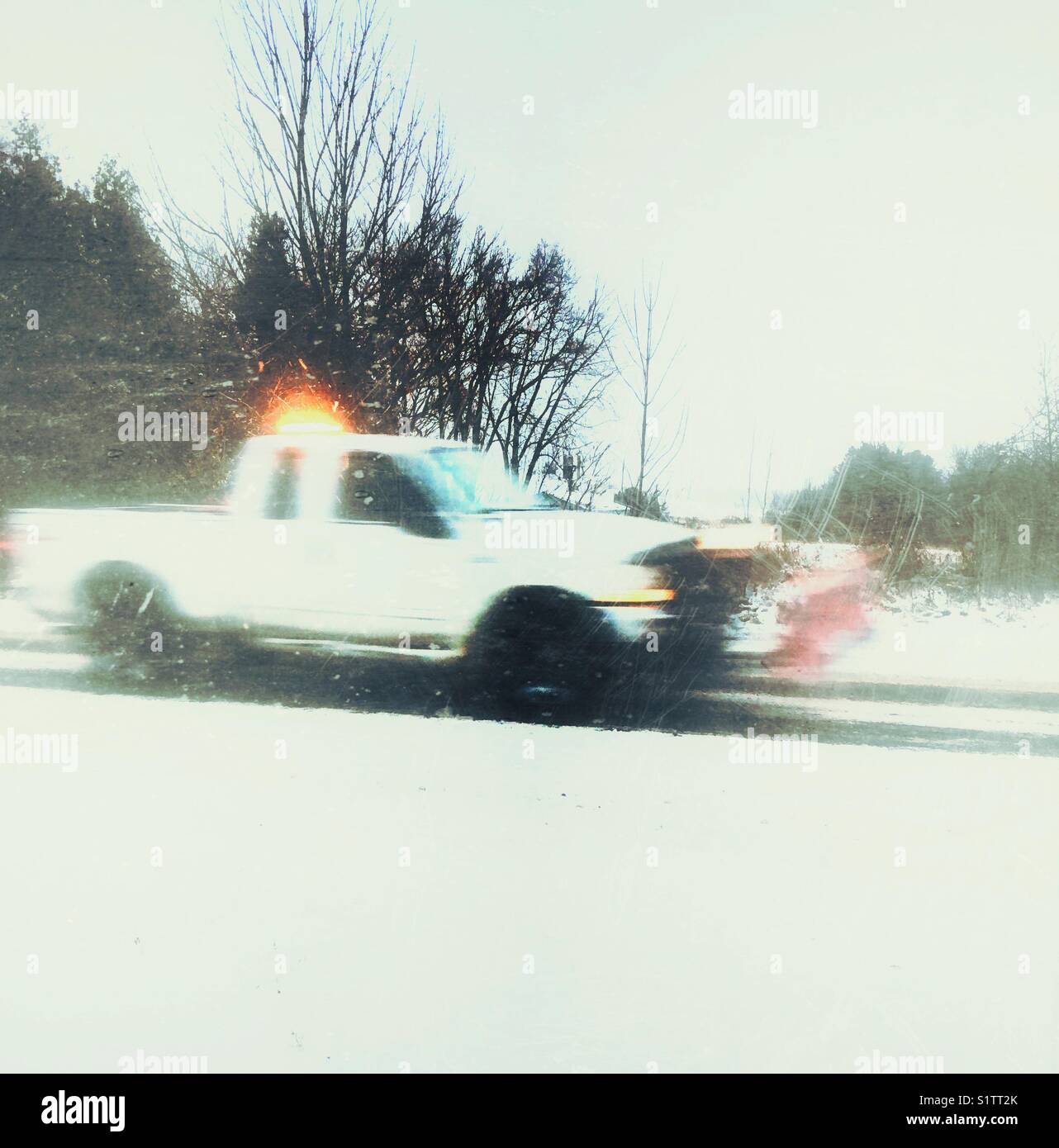 Camioncino con spazzaneve pala attaccata la guida verso il basso coperto di neve strada durante una nevicata nel sud Ontario, Canada - Immagine stock catturata con smartphone