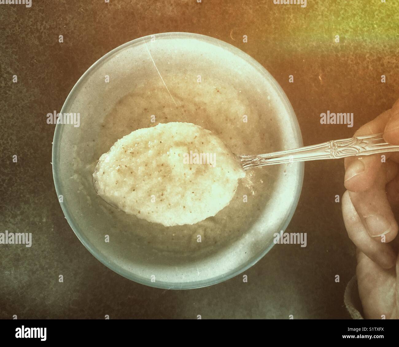Cucchiaio di frumento cereali caldi (porridge) tenutasi a mano sul vaso circa per mangiare Foto Stock