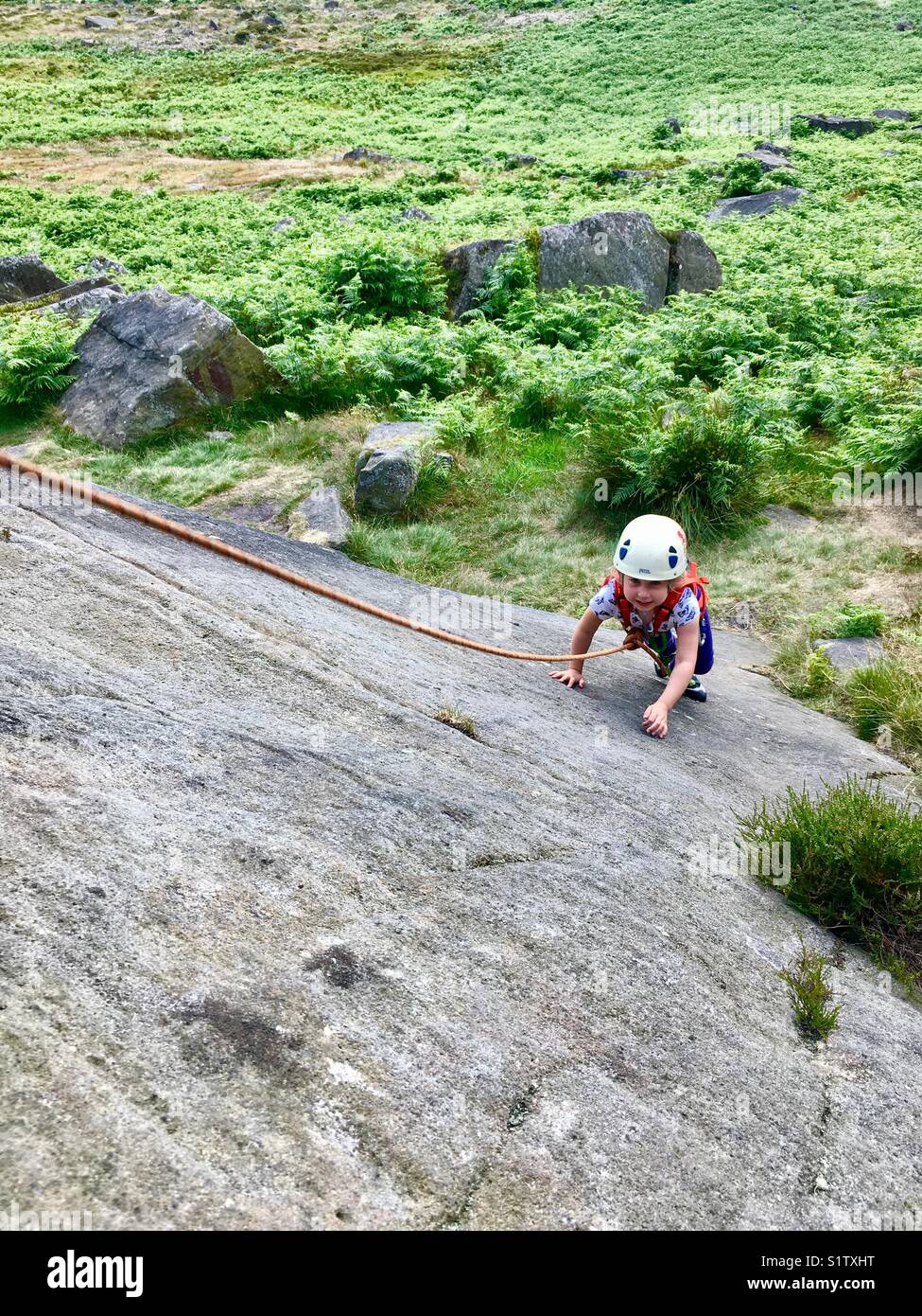 Ragazza giovane arrampicata su roccia a Burbage North nel Peak District. Foto Stock