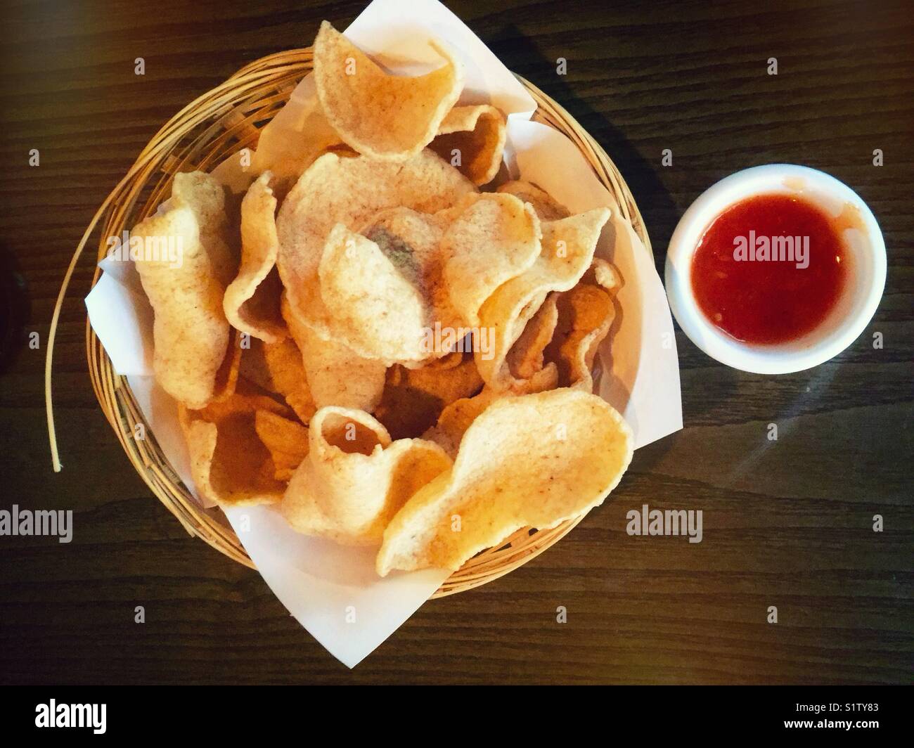 Un cestello di cracker ai gamberi con una ciotola di salsa al peperoncino dolce. Foto Stock