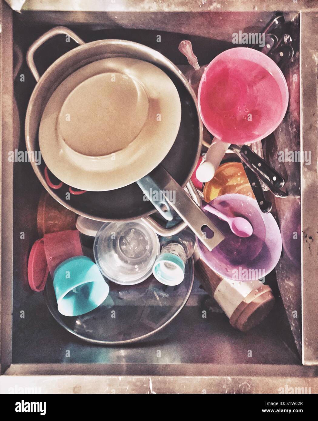 Lavello in acciaio inox pieno di sporco piatti casuali comprese pentole, posate di plastica e i bambini i piatti di Foto Stock