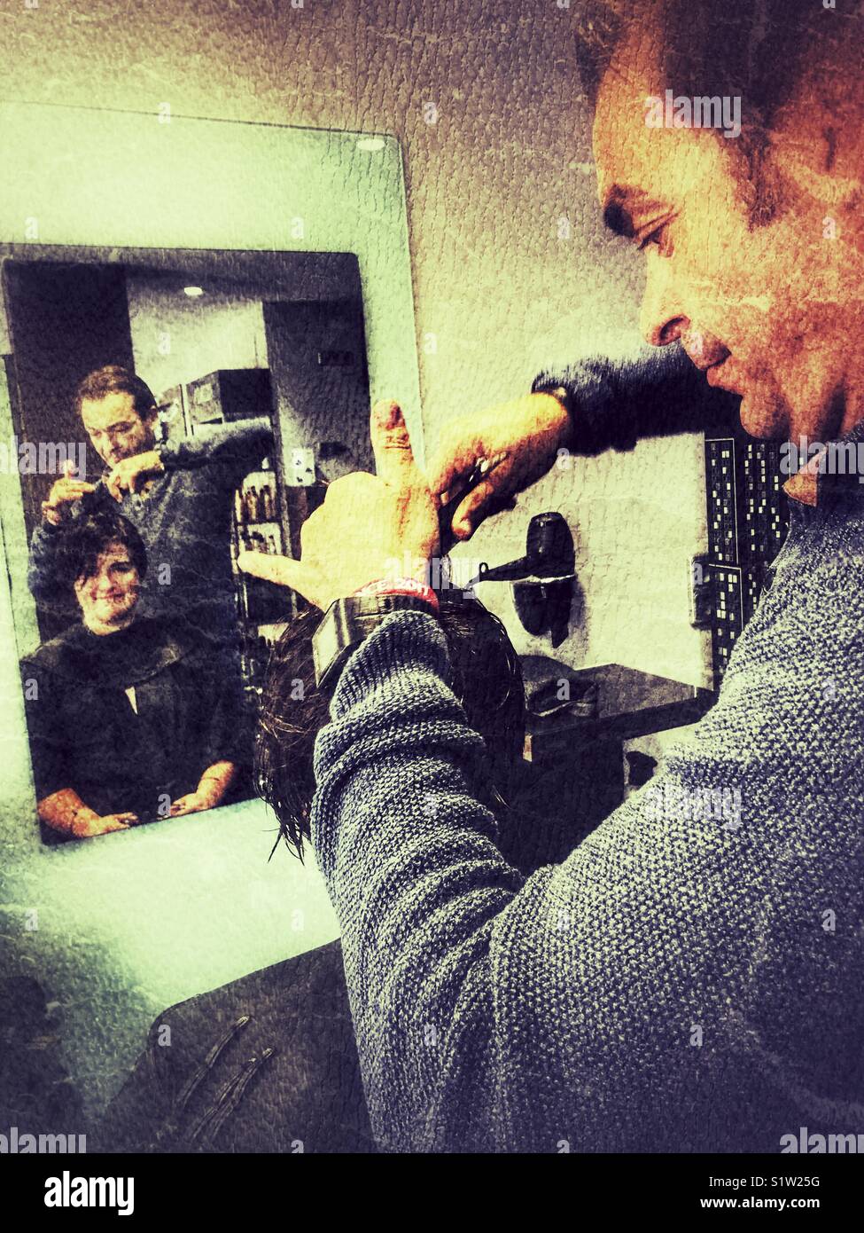 Parrucchiere maschio il taglio di una giovane donna capelli - Immagine stock catturata con smartphone