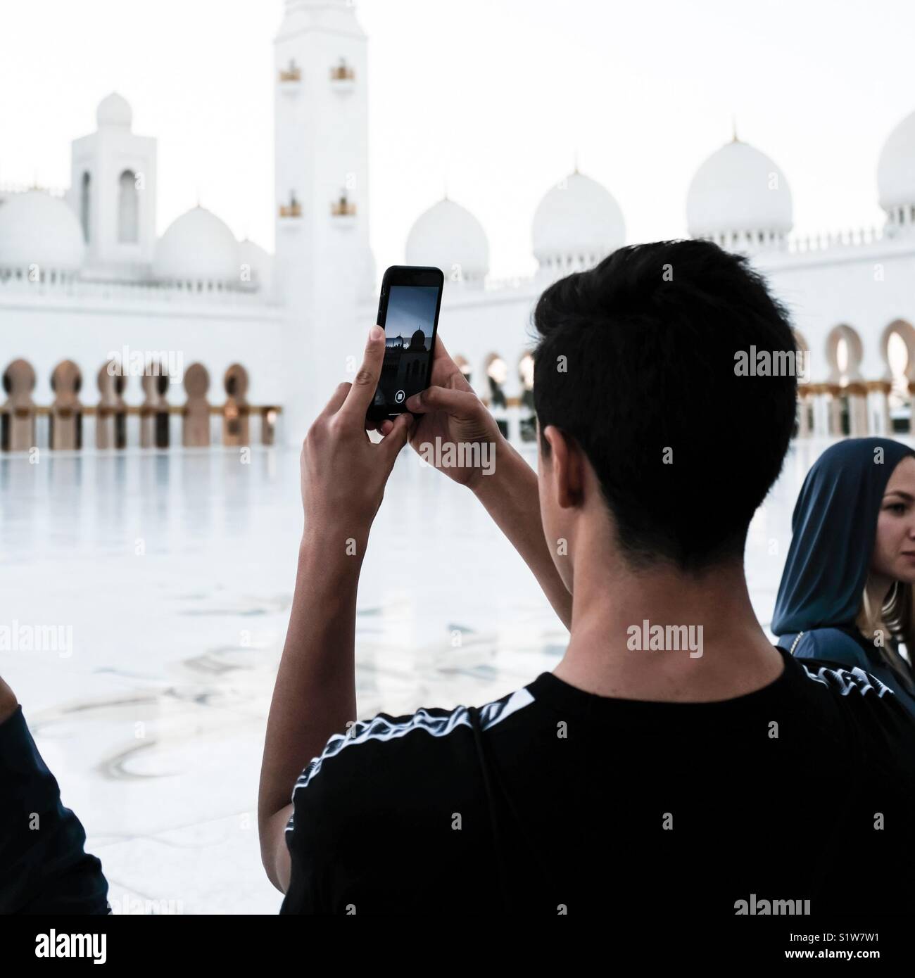 Giovane uomo prende una foto al Sheikh Zayed grande moschea sul suo iPhone Foto Stock