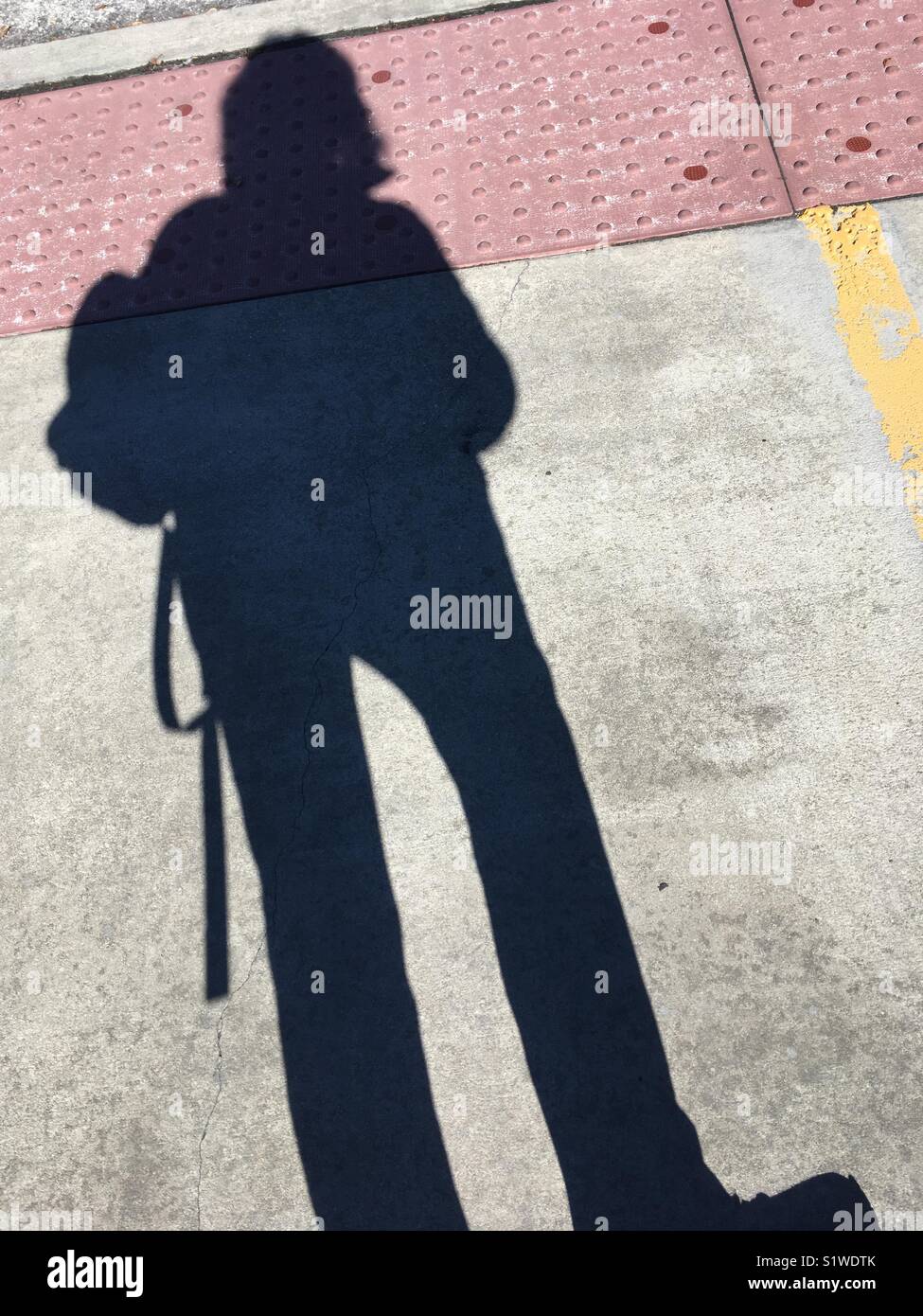 Ombra selfie delle zampe lunghe donna in Street indossare uno zaino Foto Stock