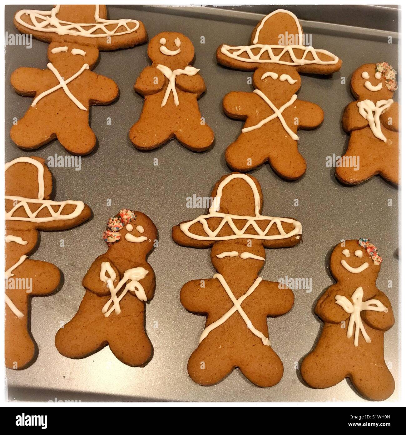 Un foglio di cottura viene riempito con messicano ispirato gingerbread cookies dotate di pan di zenzero di uomini in sombreros e gingerbread donne azienda calla gigli. Foto Stock