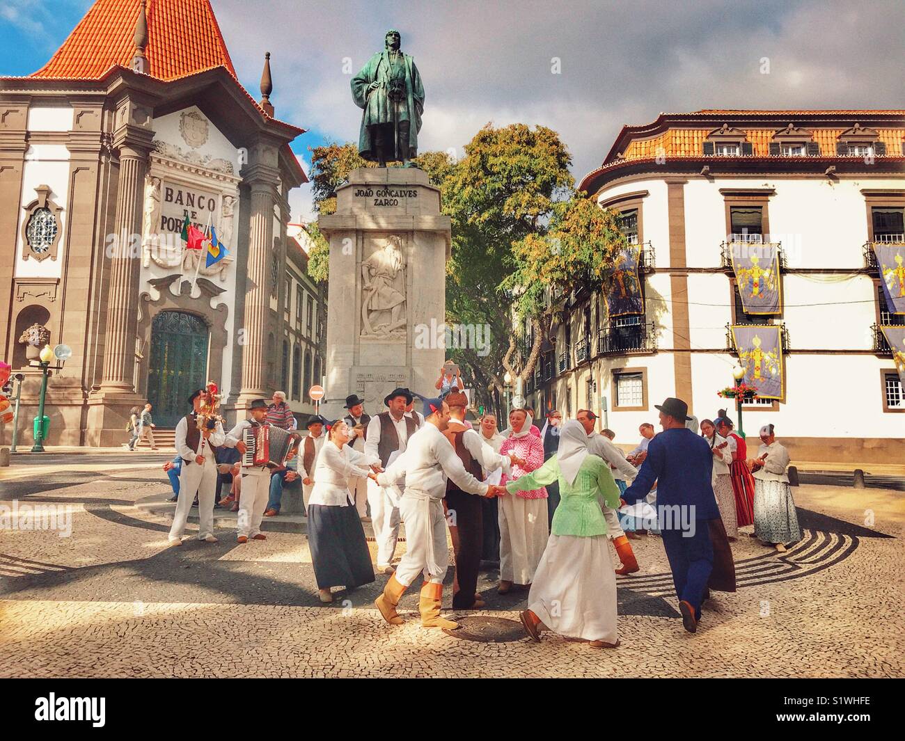 I musicisti folk e ballerini eseguono davanti alla statua di Zarco, con la mitica Banca del Portogallo in background. Funchal, Madeira, Portogallo Foto Stock