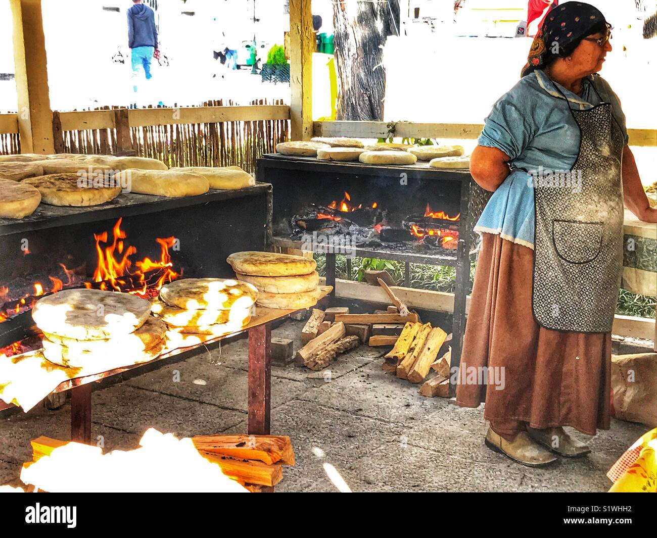 Senior donna in abito tradizionale per la cottura sul fuoco aperto al mercato di Natale, Funchal, Madeira, Portogallo - Immagine stock catturata con smartphone