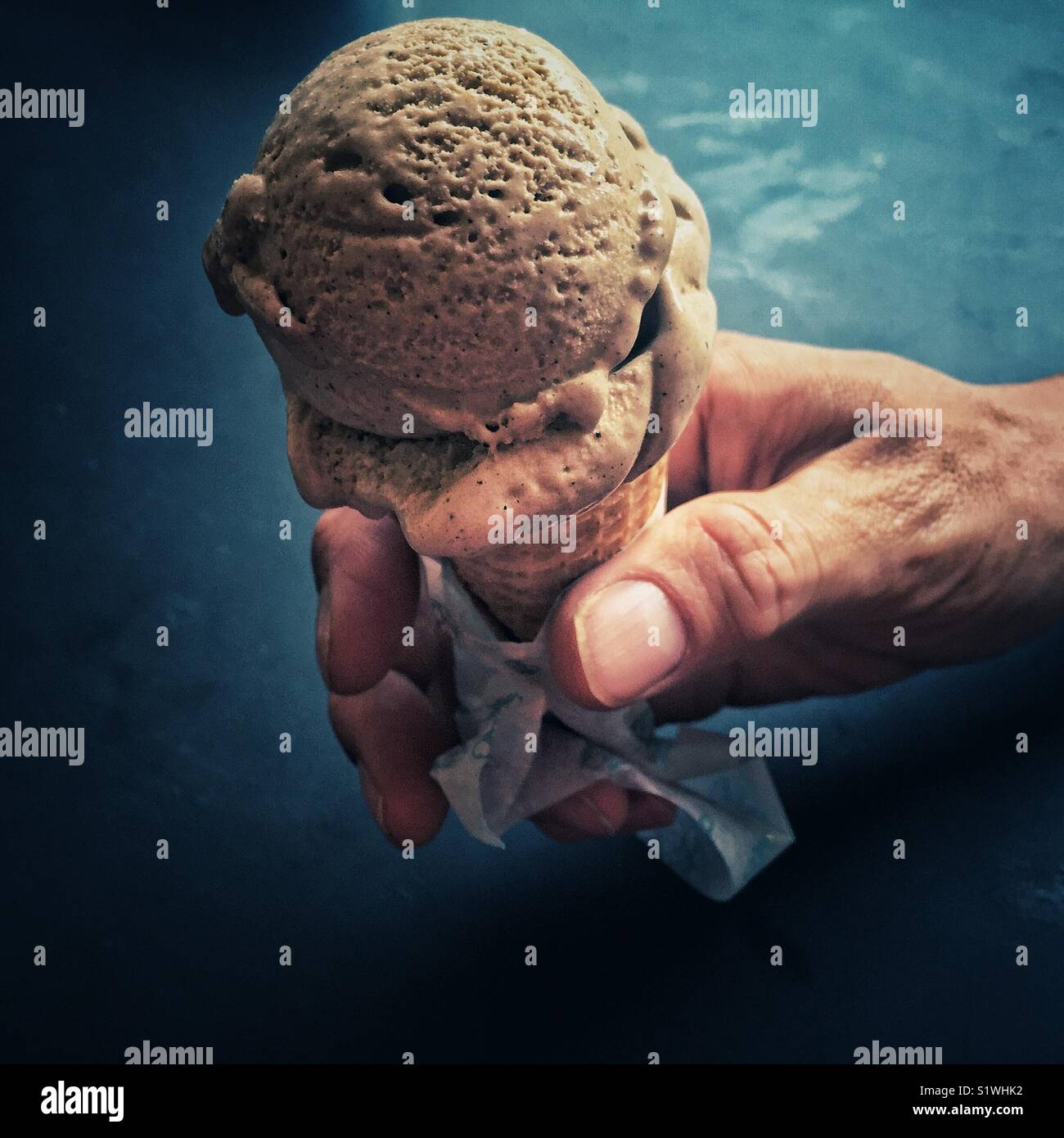 L'uomo la mano che regge il gelato al cioccolato di cono Foto Stock