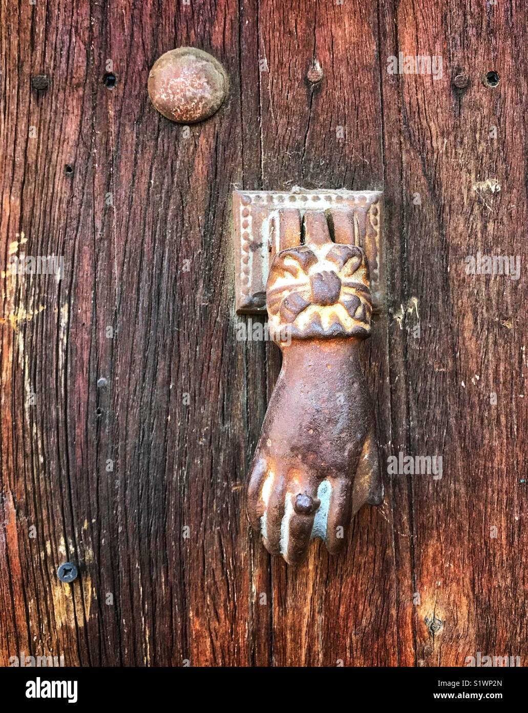 Una mano femminile porta respingente aggiunge un tocco estroso di questa antica porta di legno in Ajijic, Messico. Foto Stock