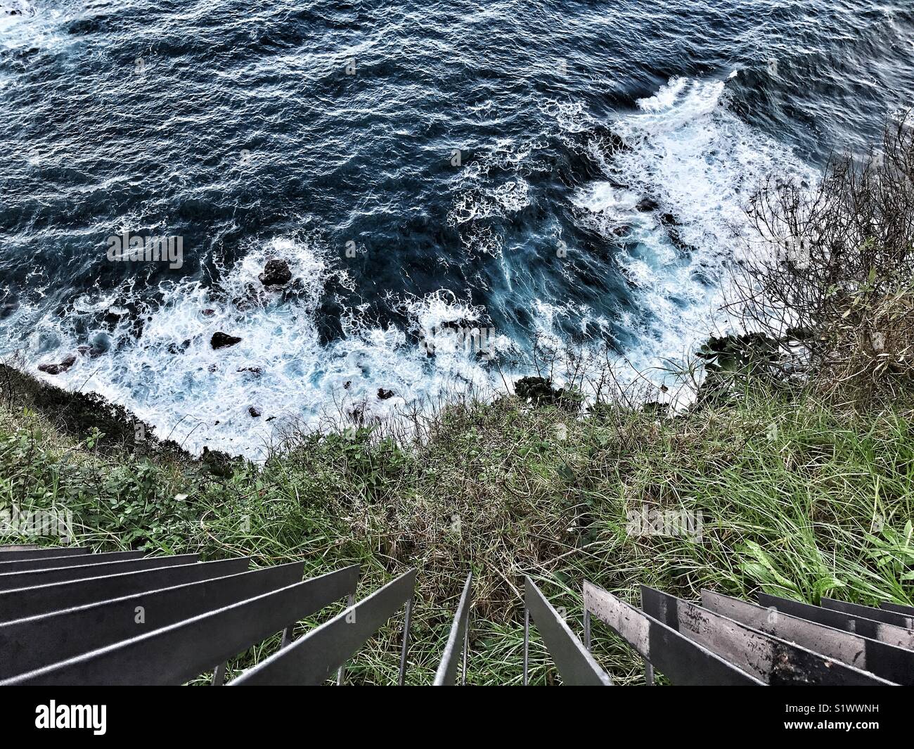 Cerca su ringhiere in ferro, giù per il dirupo per la costa rocciosa e l'oceano, ad alto angolo di visione, Madeira, Portogallo - Immagine stock catturata con smartphone