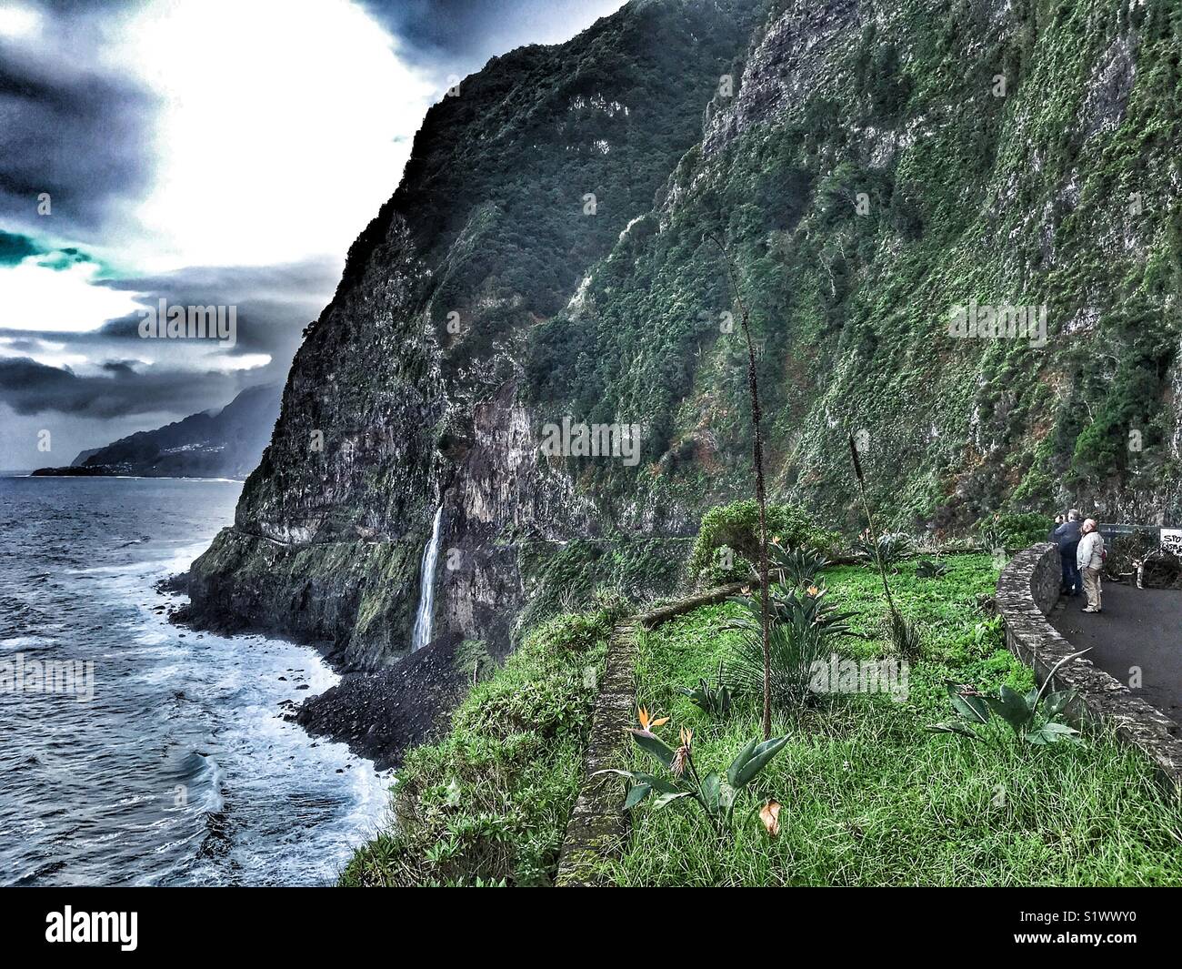 I turisti ammirando la vista con Bridal Veil Falls e la vecchia strada costiera, chiuse a causa di frane e smottamenti, Madeira, Portogallo - Immagine stock catturata con smartphone