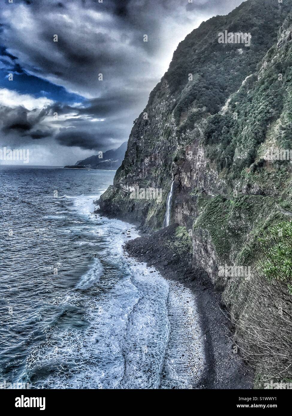 Vista costiera con Bridal Veil Falls e la vecchia strada costiera, chiuse a causa di frane e smottamenti, Madeira, Portogallo - Immagine stock catturata con smartphone