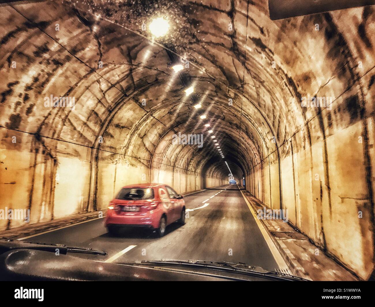 Rischia di essere superato da un auto rossa durante la guida attraverso una delle numerose gallerie stradali sull isola di Madeira, Portogallo - Immagine stock catturata con smartphone