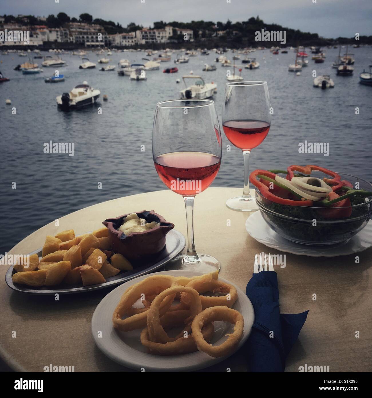 Due gas di rose e tapas su tavola, con porto in background, Cadaques, Alt Emporda comarca in Costa Brava Catalogna - Immagine stock catturata con smartphone
