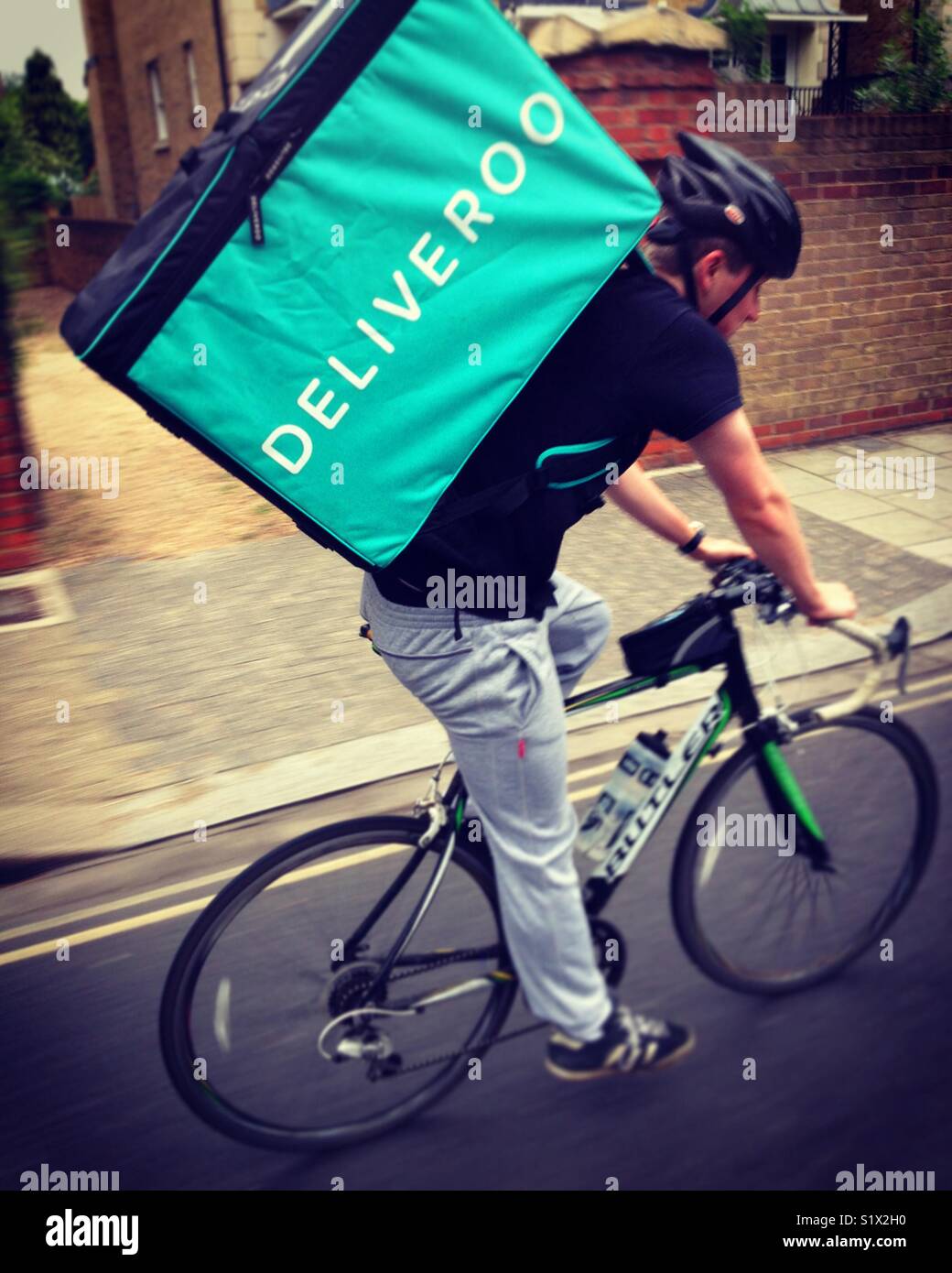 Ciclo Deliveroo courier portante un pasto da asporto per un client dopo aver ritirato presso un ristorante. Regno Unito Foto Stock