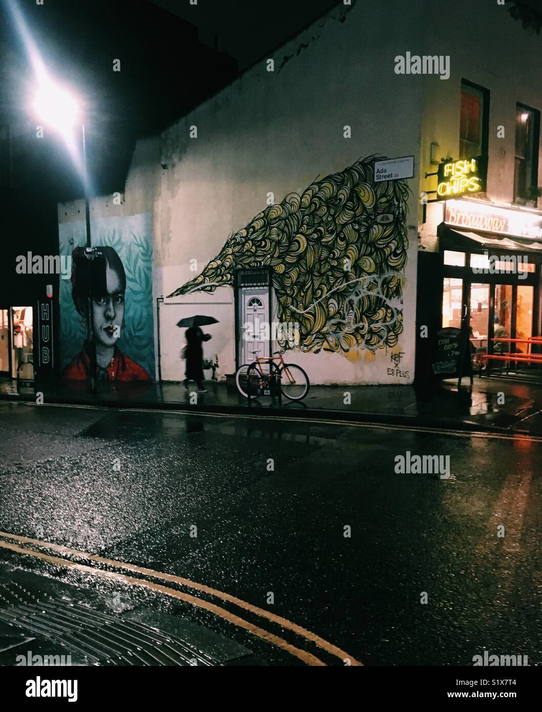 Donna passando murales situato in Broadway Market di East London REGNO UNITO - Immagine stock catturata con smartphone