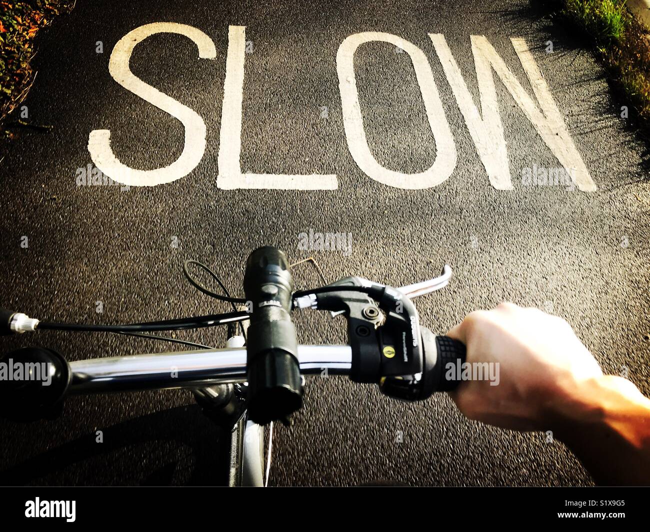 Ciclista avvicinandosi ad un segno lento la marcatura sulla strada - Immagine stock catturata con smartphone