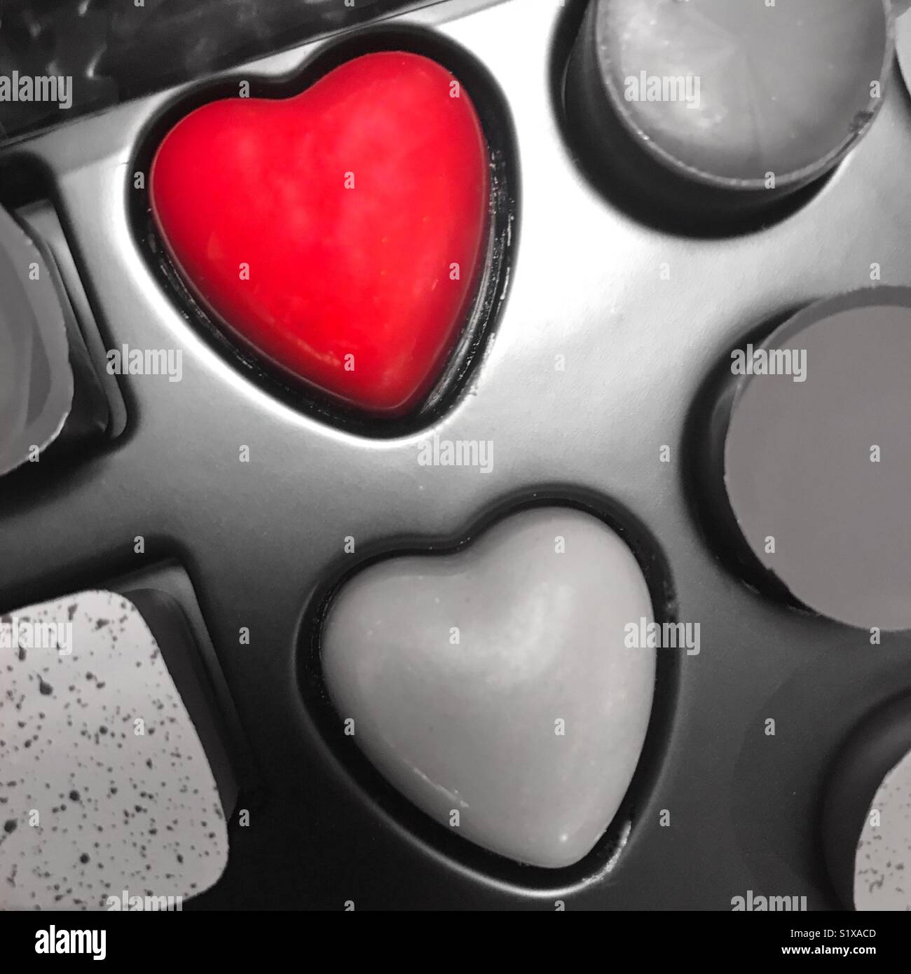 Una scatola di cioccolatini dove il cuore rosso pezzo sagomato è accentuata e il resto dissaturato - Immagine stock catturata con smartphone