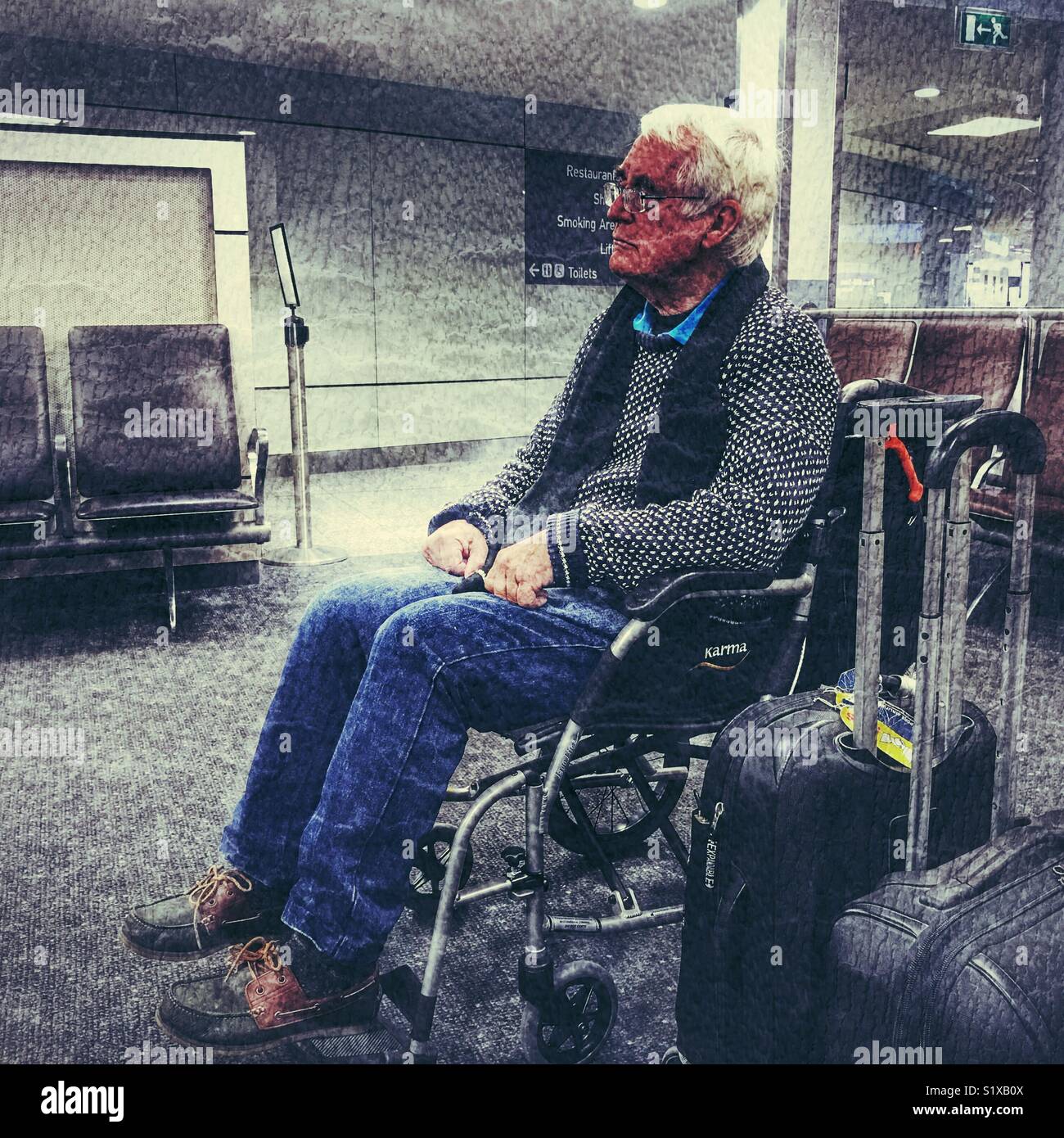 Senior uomo in sedia a rotelle in attesa in area dedicata per i passeggeri che necessitano di assistenza a bordo dell'aereo, l'aeroporto di Bristol, Inghilterra Foto Stock