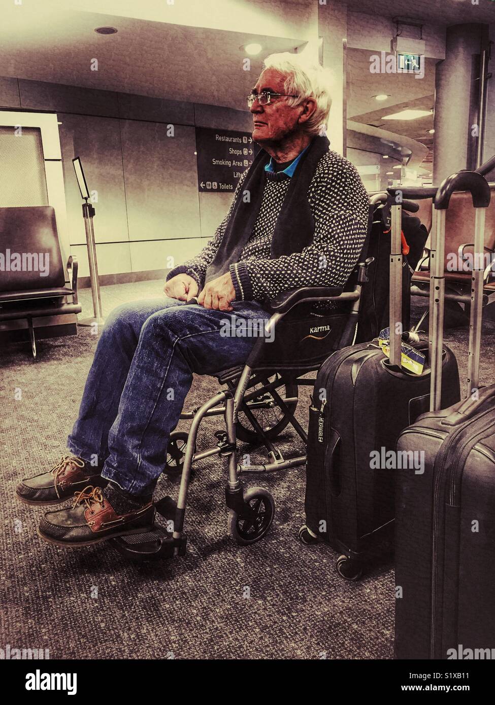 Senior uomo in sedia a rotelle in attesa in area dedicata per i passeggeri che necessitano di assistenza a bordo dell'aereo, l'aeroporto di Bristol, Inghilterra Foto Stock