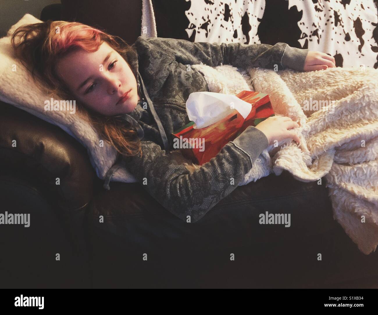 Ragazza malati con influenza sdraiato sul divano tenendo un casella di tessuti Foto Stock