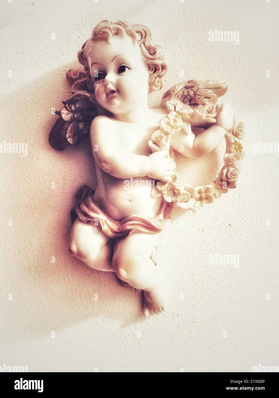 Angelo scultura a parete con ghirlanda di fiori - Immagine stock catturata con smartphone