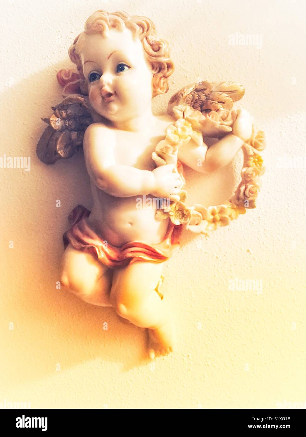 Angelo scultura a parete con ghirlanda di fiori - Immagine stock catturata con smartphone
