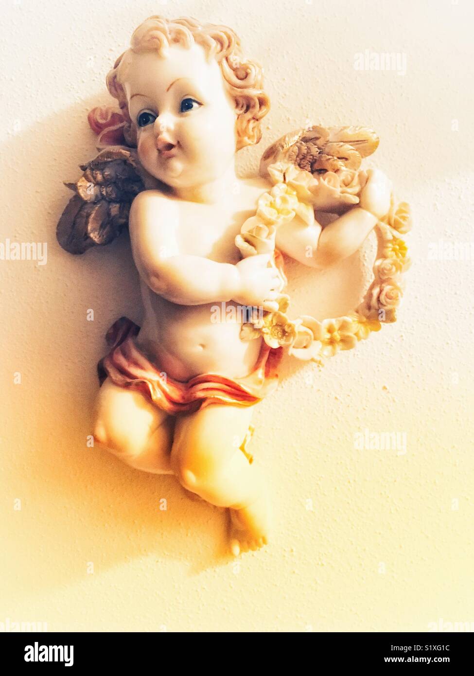 Angelo scultura a parete con ghirlanda di fiori - Immagine stock catturata con smartphone