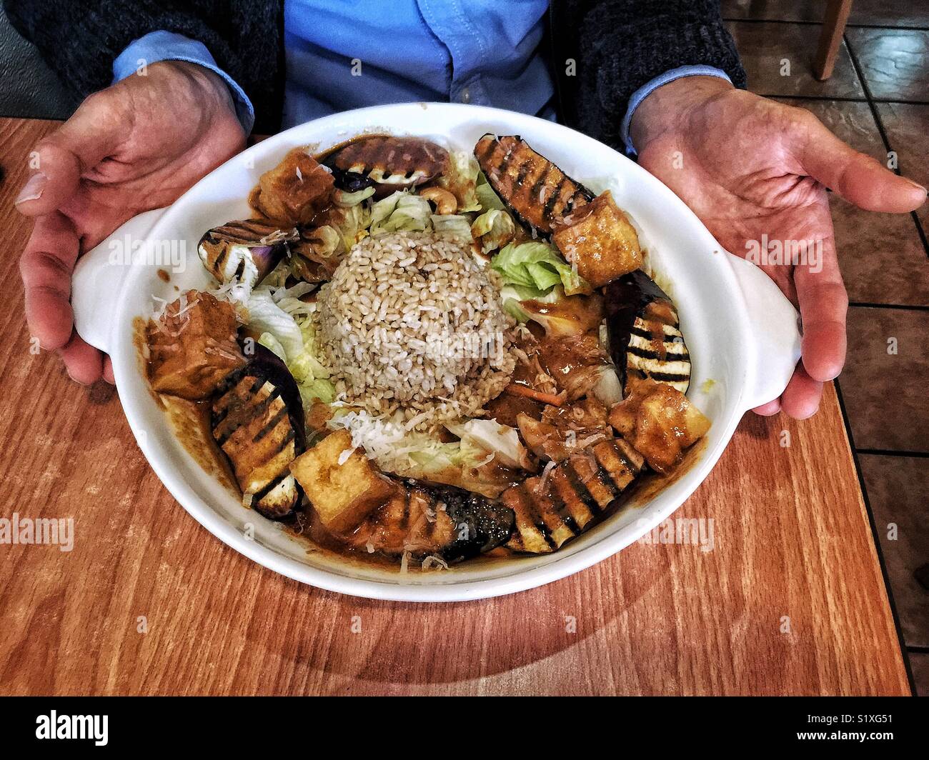 Mani grande ciotola del vegan antipasto di melanzane e tofu sul riso - Immagine stock catturata con smartphone