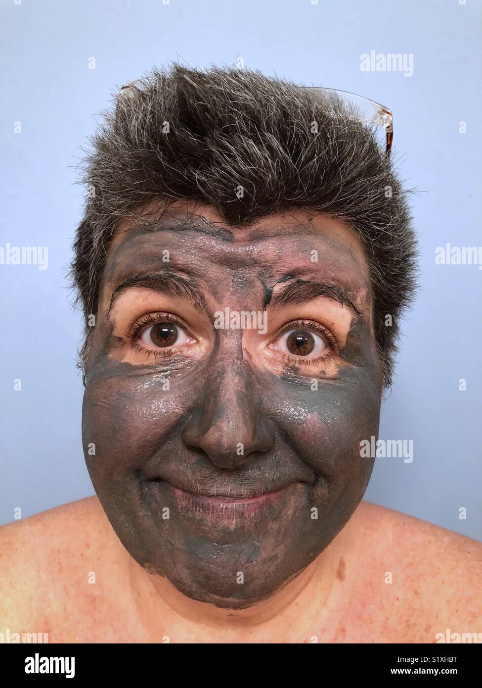 Un ritratto di un pelo scuro Caucasian donna che indossa una maschera di fango e sorridente Foto Stock