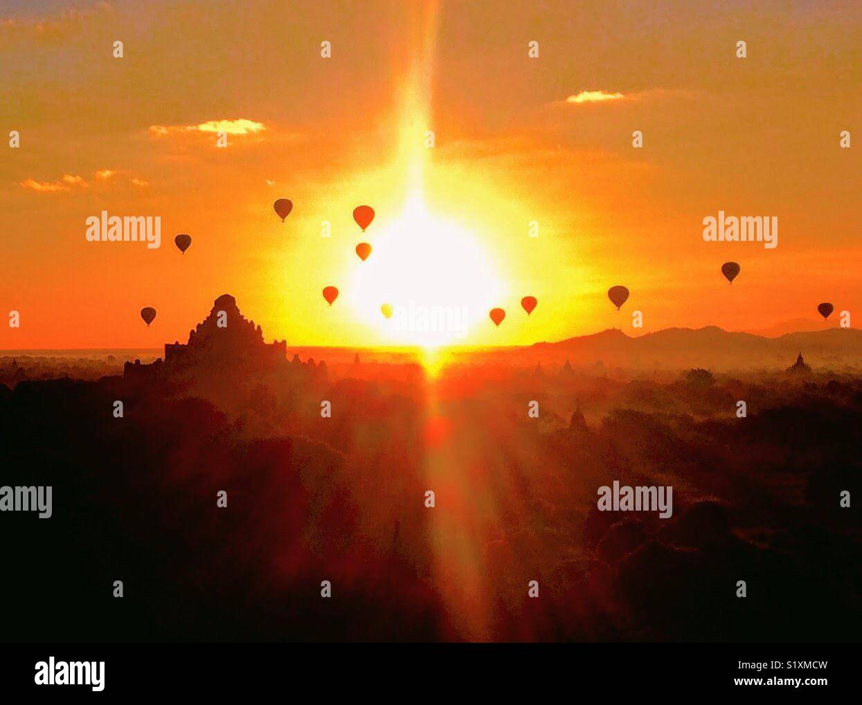I palloni ad aria calda danza in tutta la campagna birmano come il sole sorge a Bagan, Myanmar Foto Stock