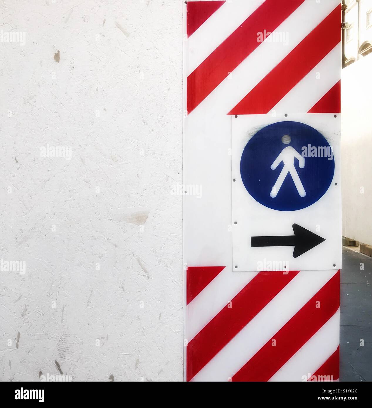 Seguire la freccia indietro, un segno per i pedoni a camminare in opere di costruzione ma il simbolo del pedone è nella direzione opposta - Immagine stock catturata con smartphone