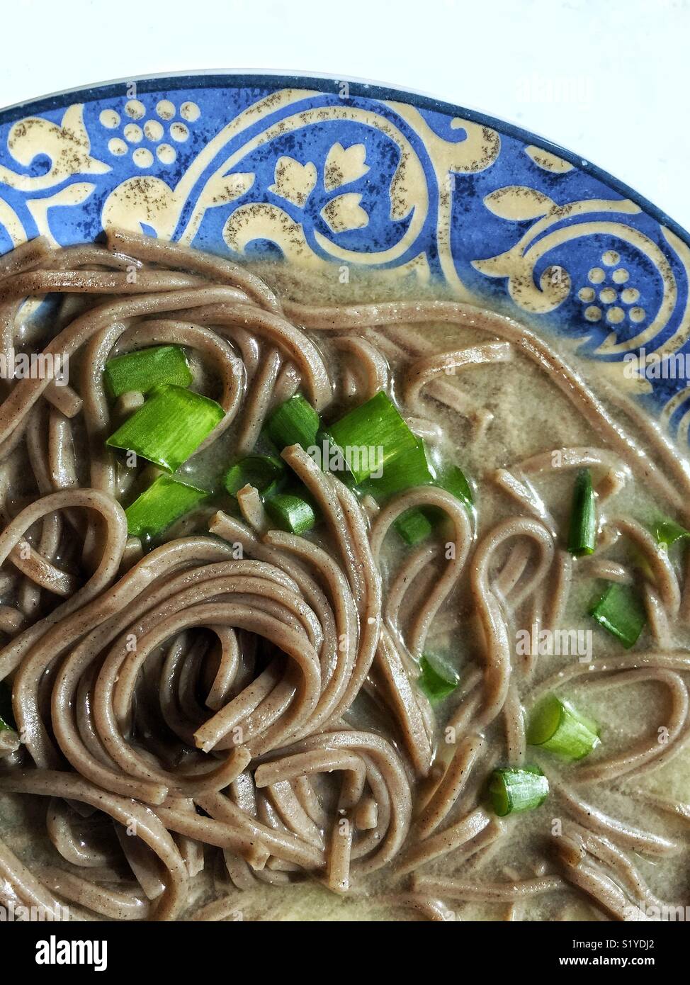 Noodles piccanti, cibo tradizionale coreano. Tagliatelle di soba di grano  saraceno e calamari con salsa di panna acida su un tavolo di pietra scura.  Vista dall'alto sfondo piatto Foto stock - Alamy