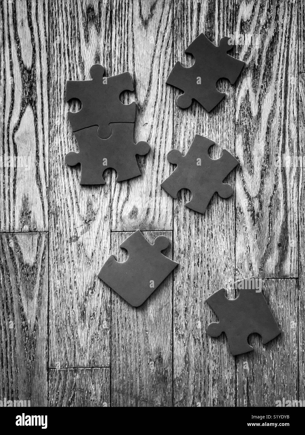Sei semplici pezzi di un puzzle su un pavimento di legno in bianco e nero Foto Stock